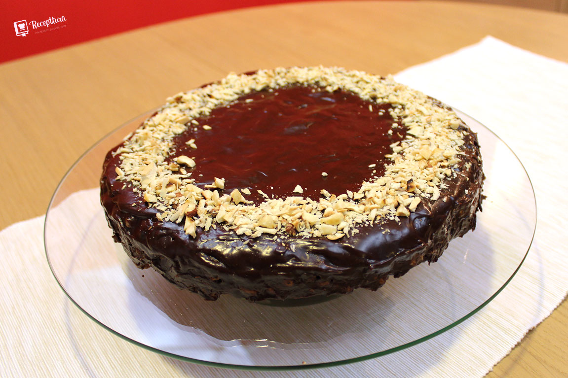 Čokoladna torta ukrašena je prepečenim lješnjacima i keksima.